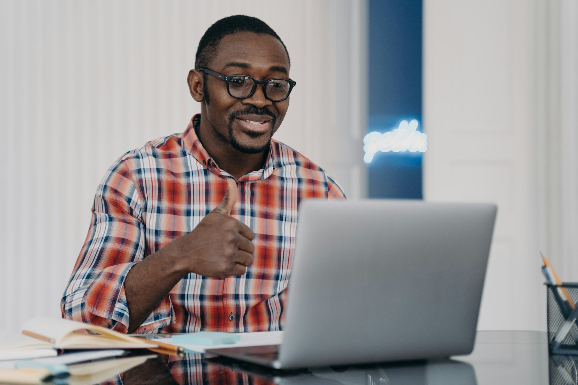 African american man shows like or thumb up gesture communicates online at laptop. Positive feedback