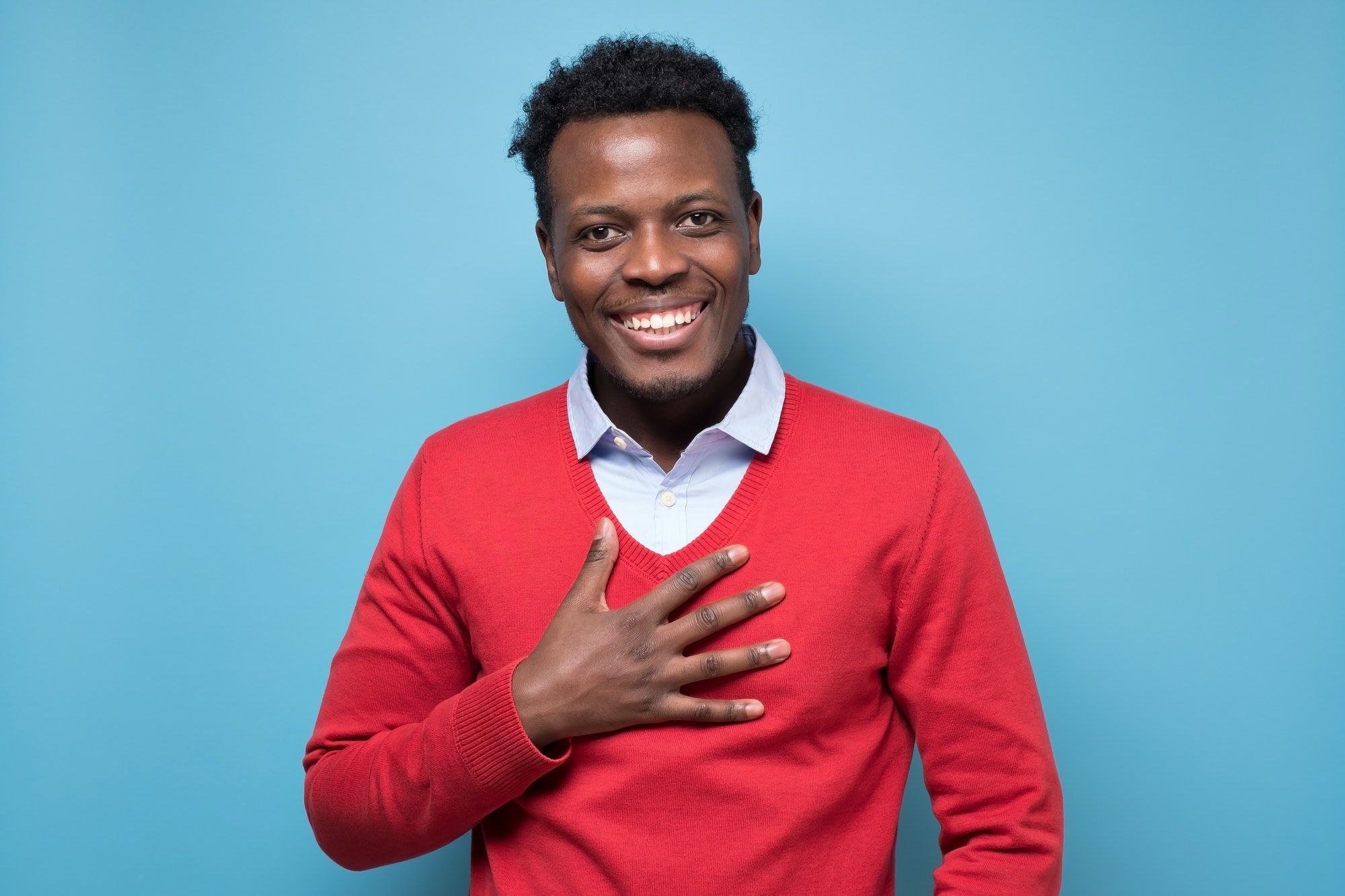 Friendly african american man keeps hands on heart, being touched by compliment